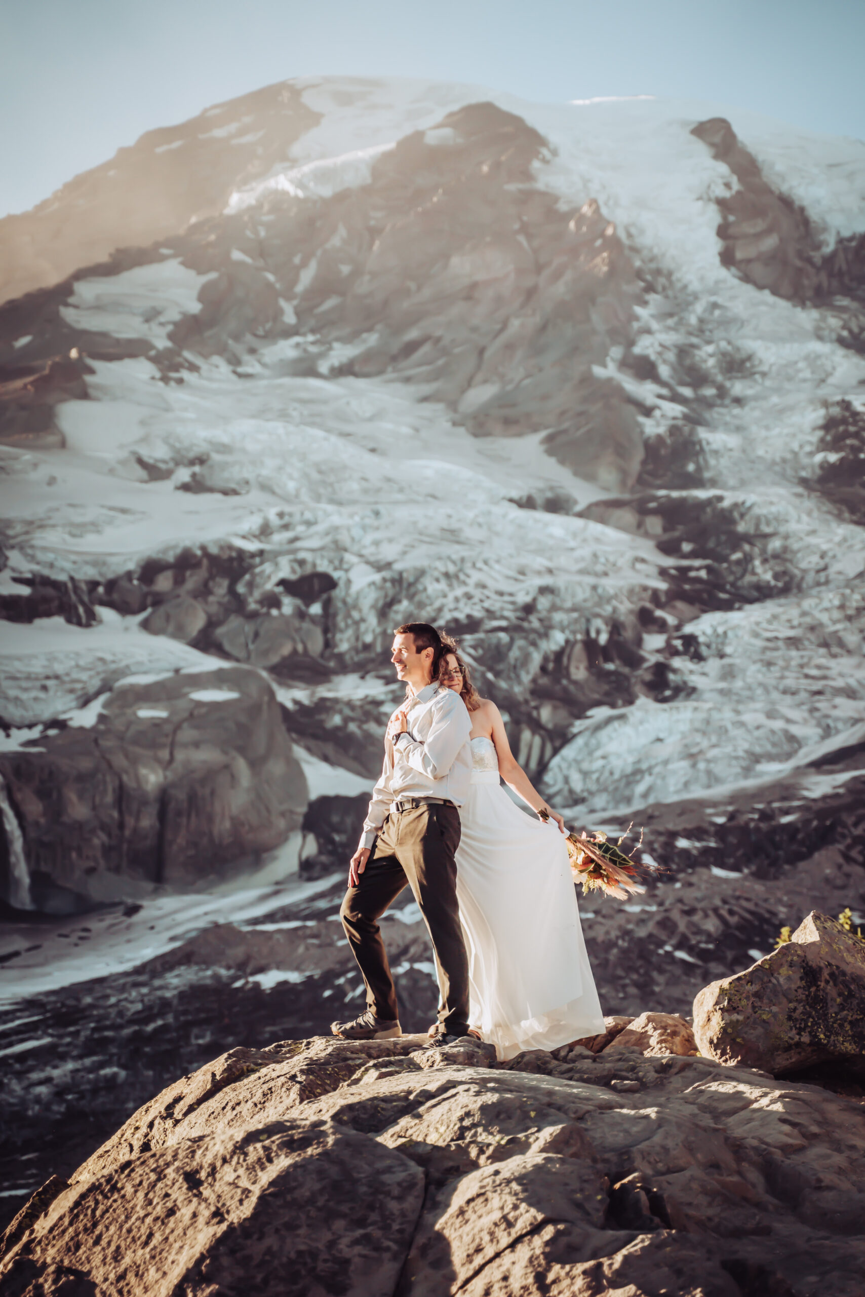 An elopement couple standing right next to Mount Rainier looking off onto the sunset