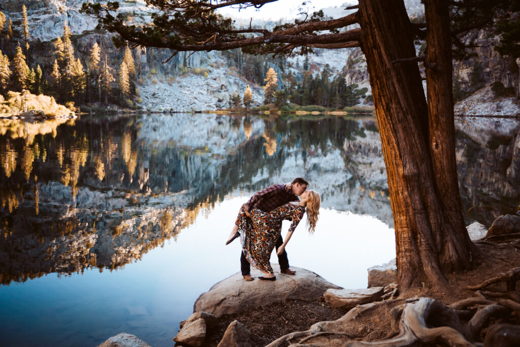 a couple doing a dip on a rock in the mountain reflection for their engagement photos in Lake Tahoe