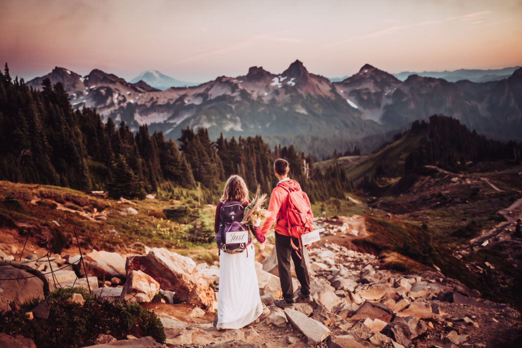 An elopement couple in hiking backpacks looking out onto the mountains in Washington 