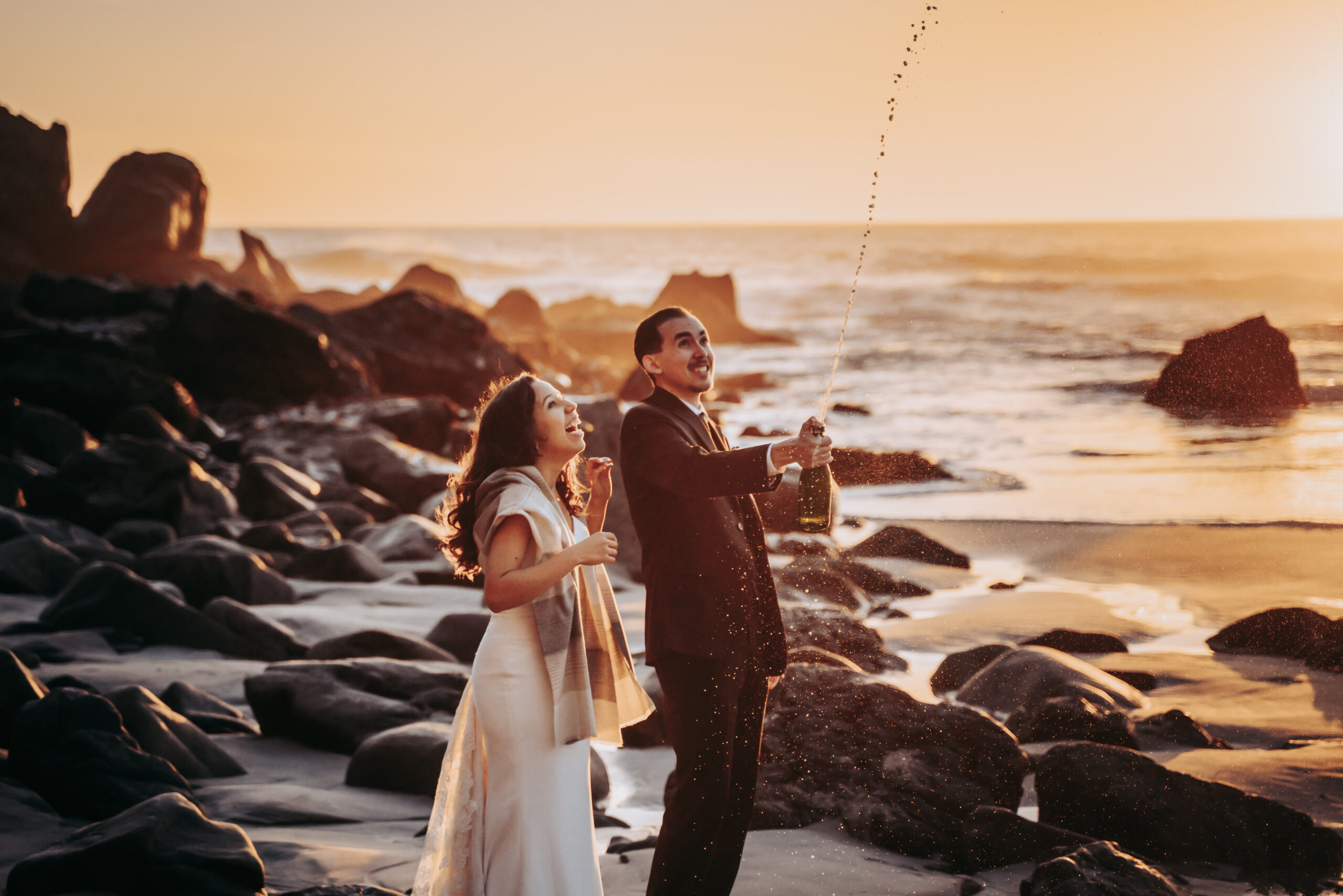 a couple popping champagne to celebrate their recent Elopement in Big Sur