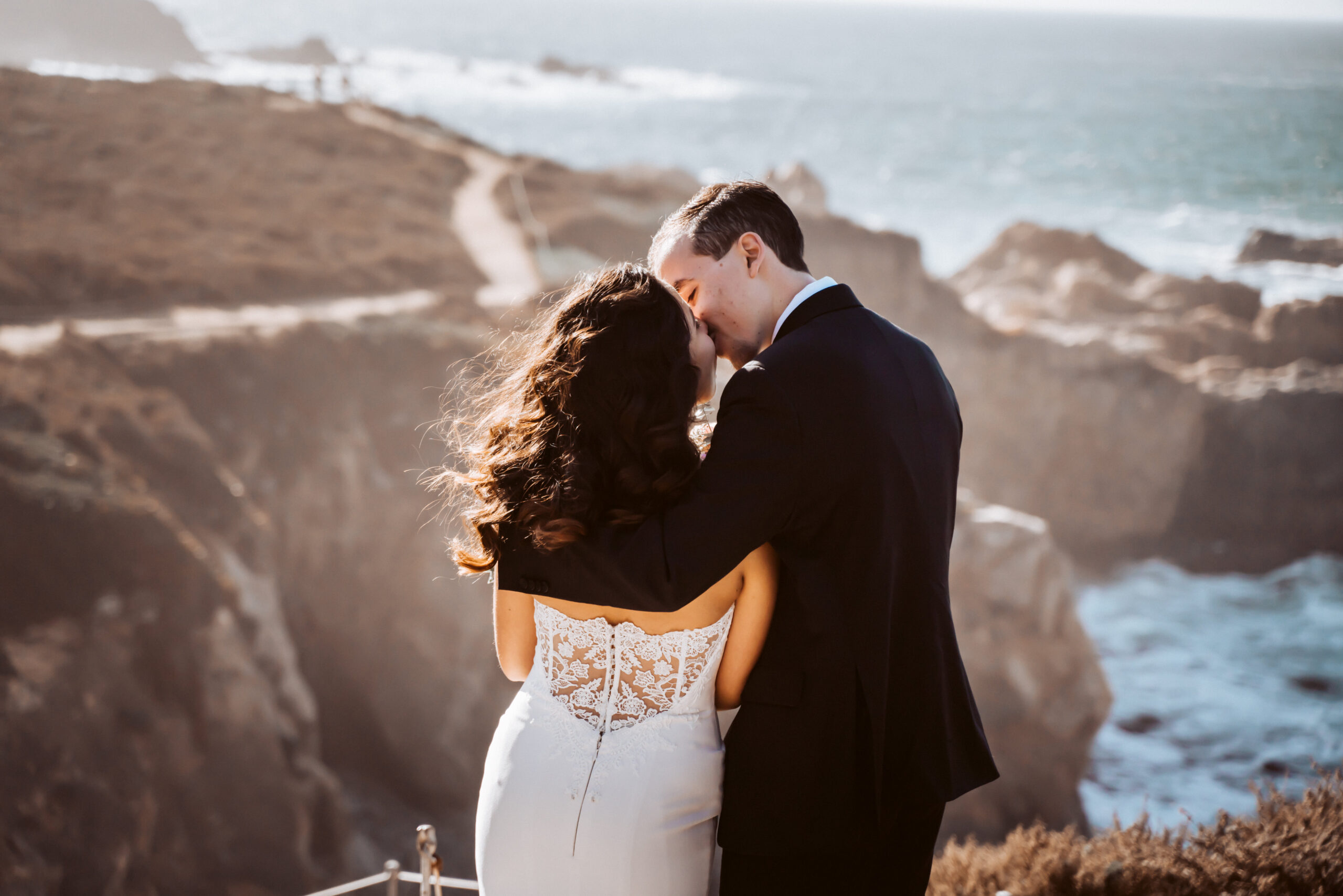 Bride and groom kissing looking out onto Big Sur