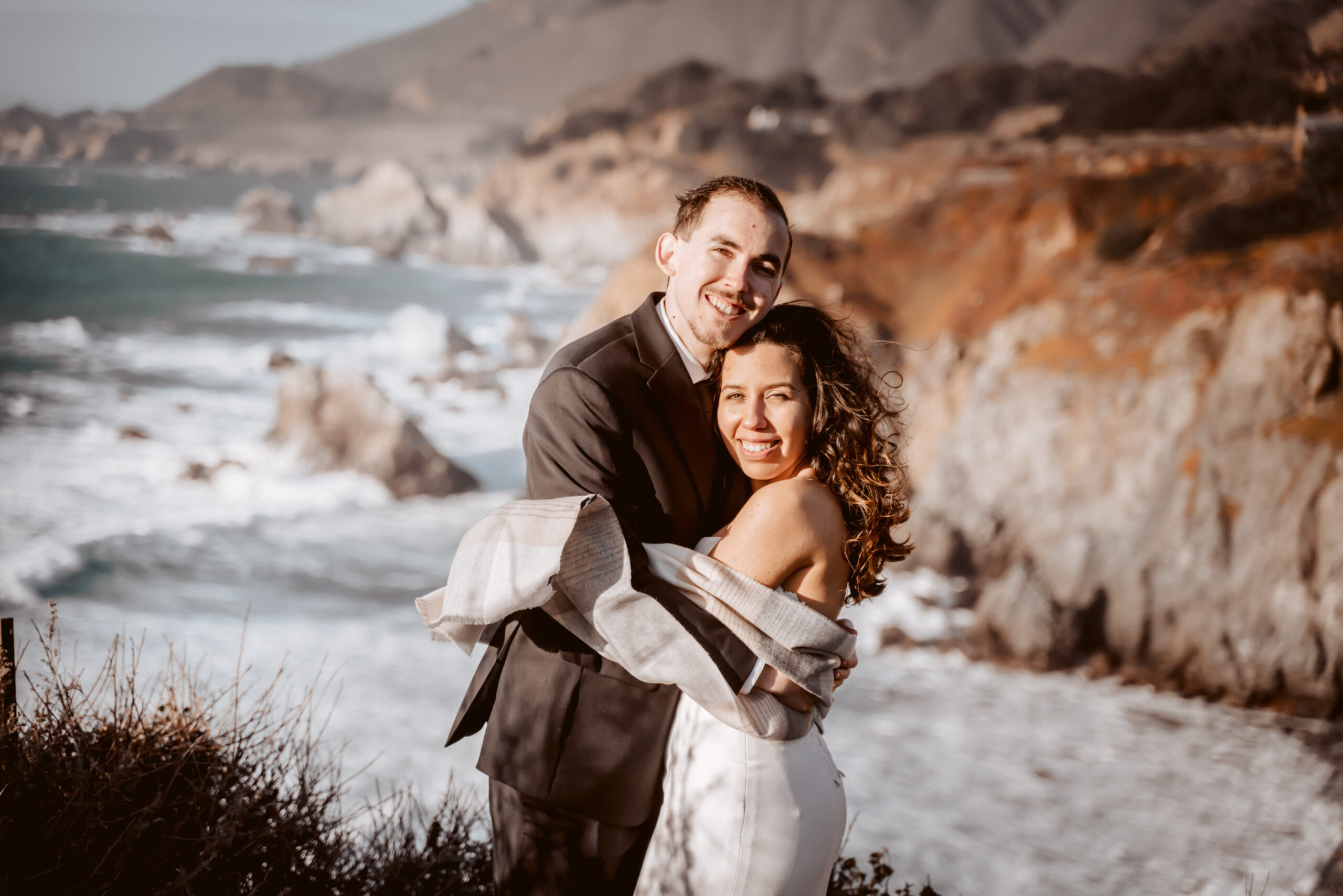 A recently married couple standing on the cliffs of Big Sur
