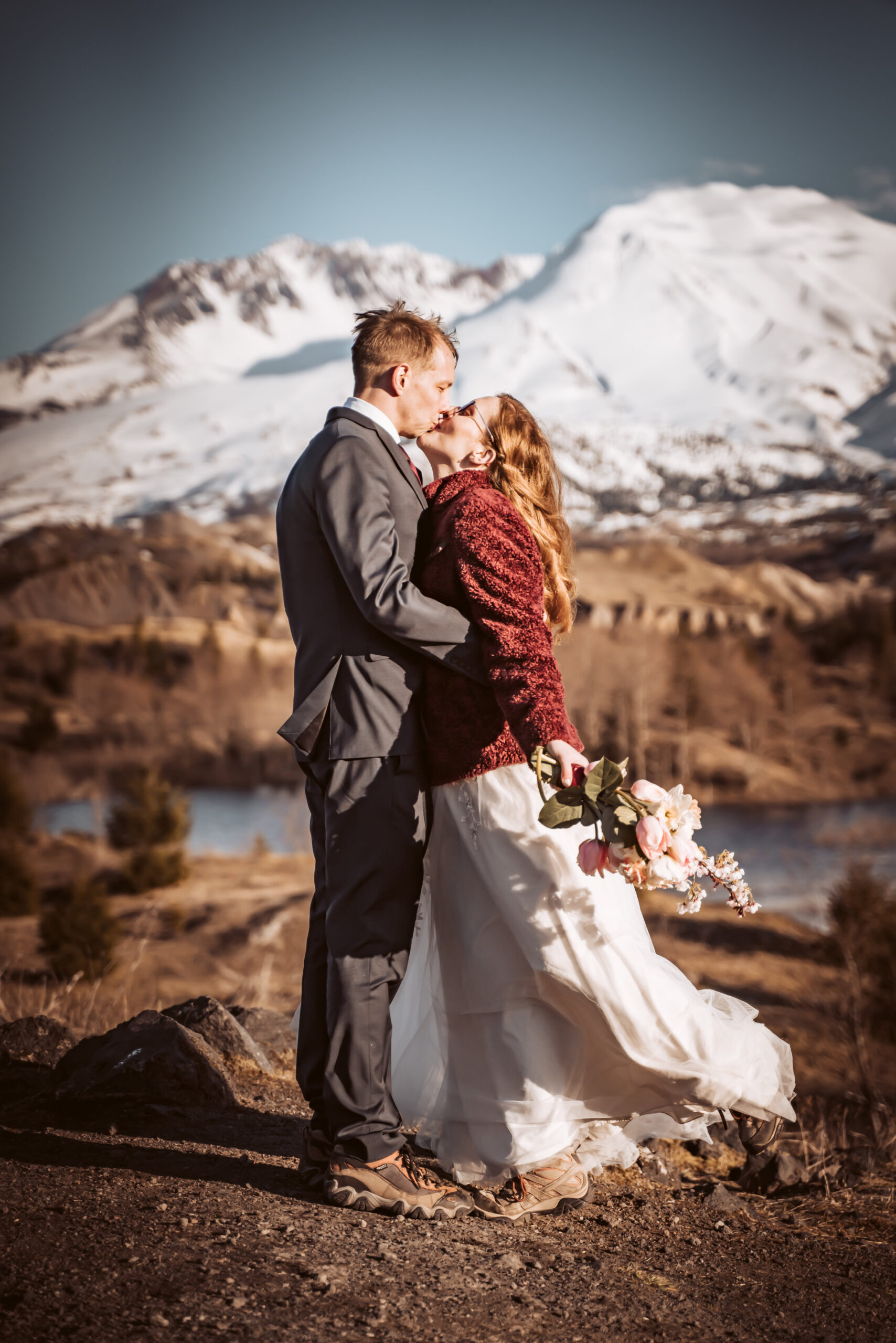  a bride and groom kissing in front of snow capped mount Saint Helens for their elopement day