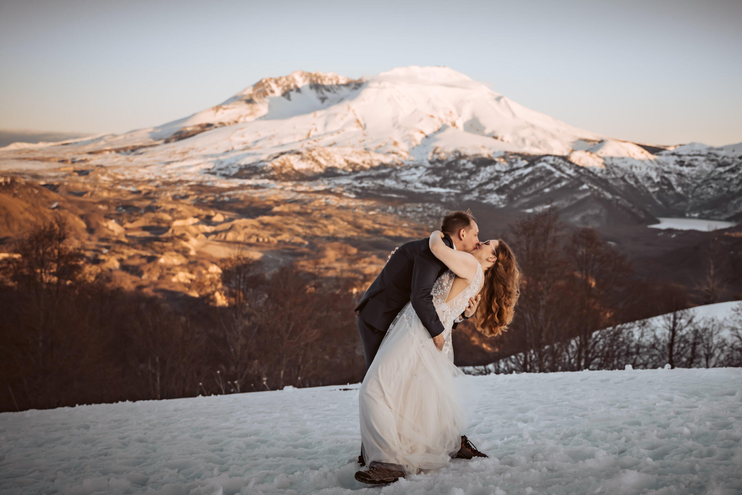 a groom dipping his bride in the snow in front of Mount Saint Helens on their wedding day