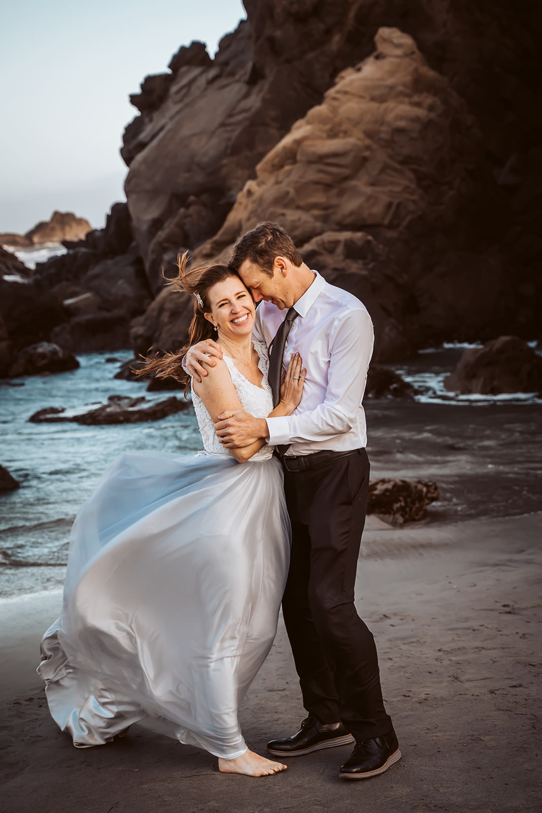 A wedding couple dancing on the beach with the ocean and cliffs of Big Sur California for their elopement day
