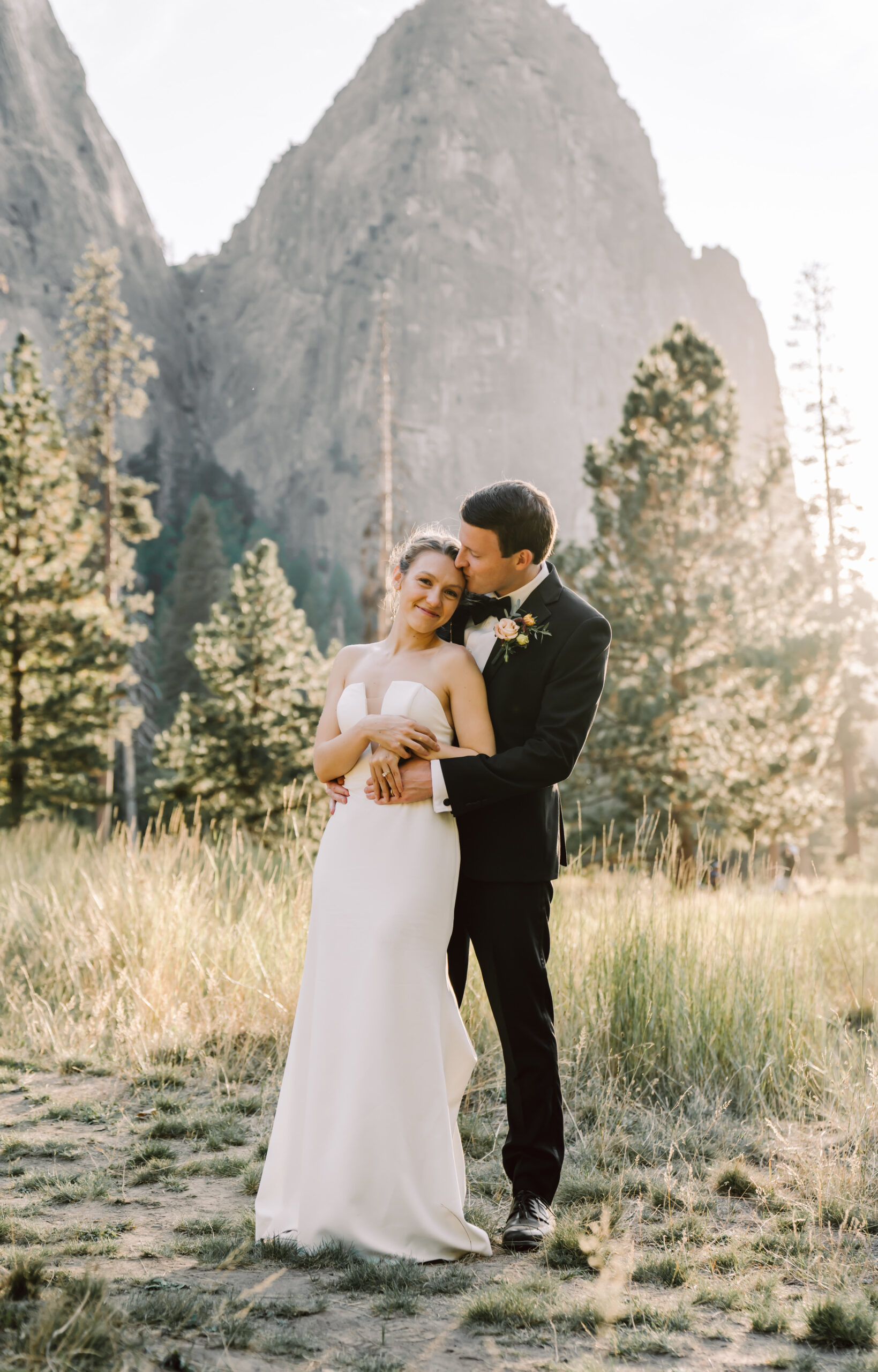 A bride and groom holding each other in front of the giant cliffs of Yosemite Valley for their elopement day 