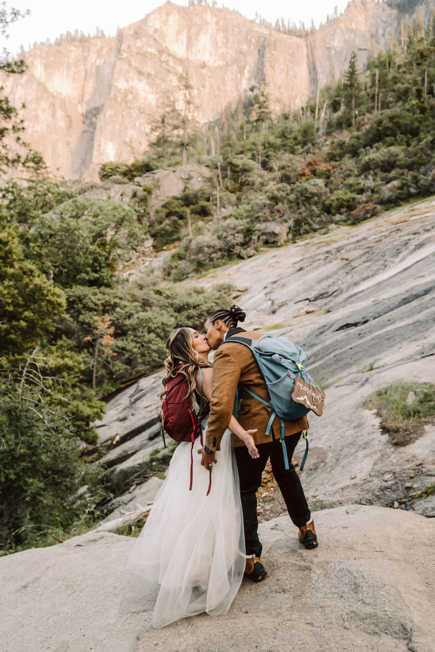 two brides kissing iin front of the giant rock cliffs of Yosemite for their elopement day