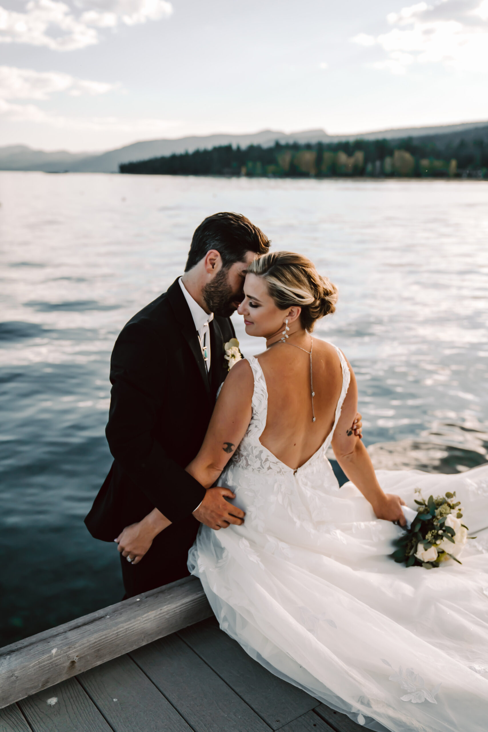 An groom whispering in his brides ear sitting on a dock in Lake Tahoe for their elopement day 