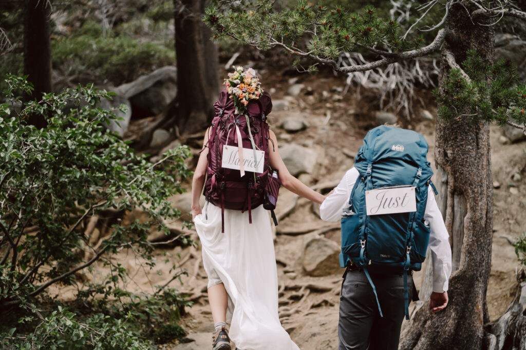 A adventure elopement couple hiking with their backpacks on and climbing over rocks