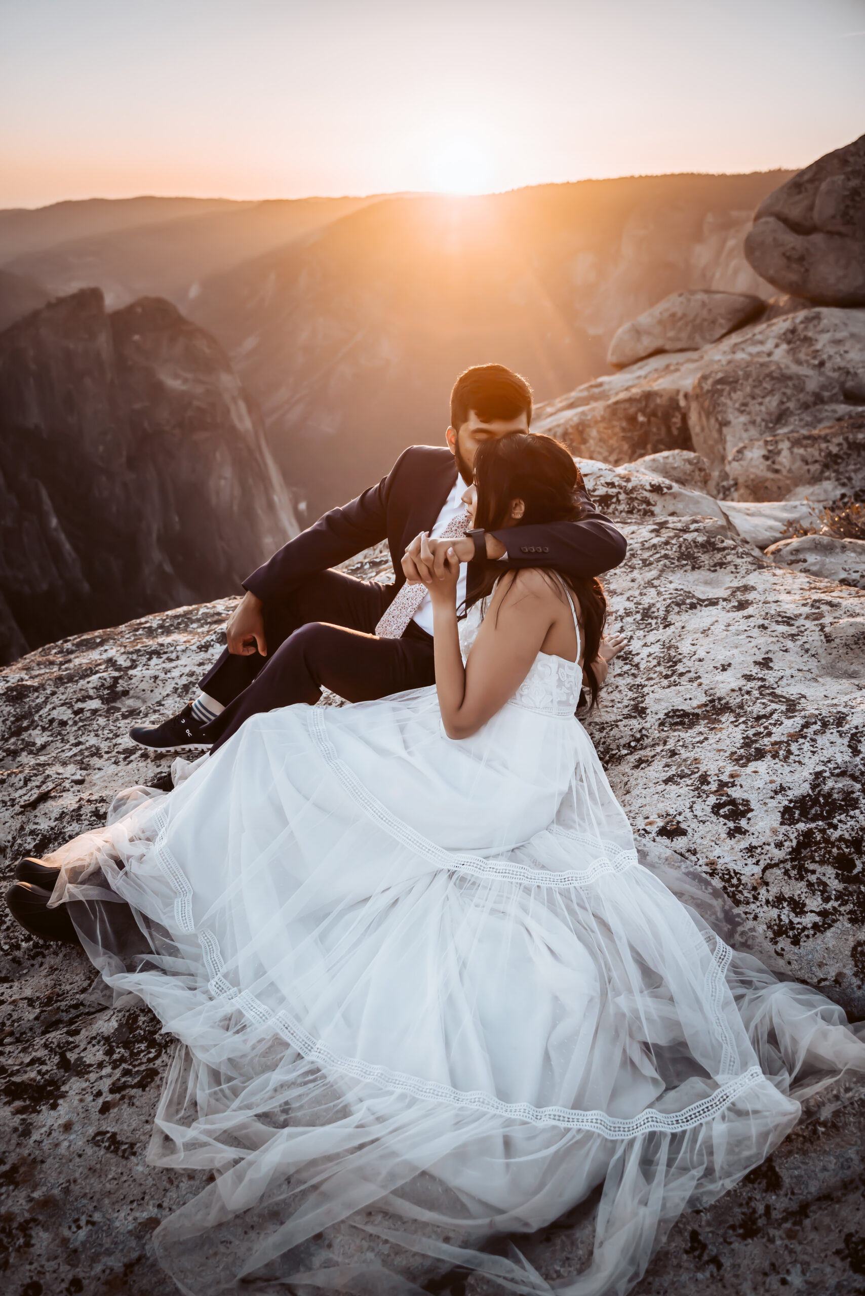 An elopement couple sitting and holding each other for their sunset Taft Point elopement in Yosemite