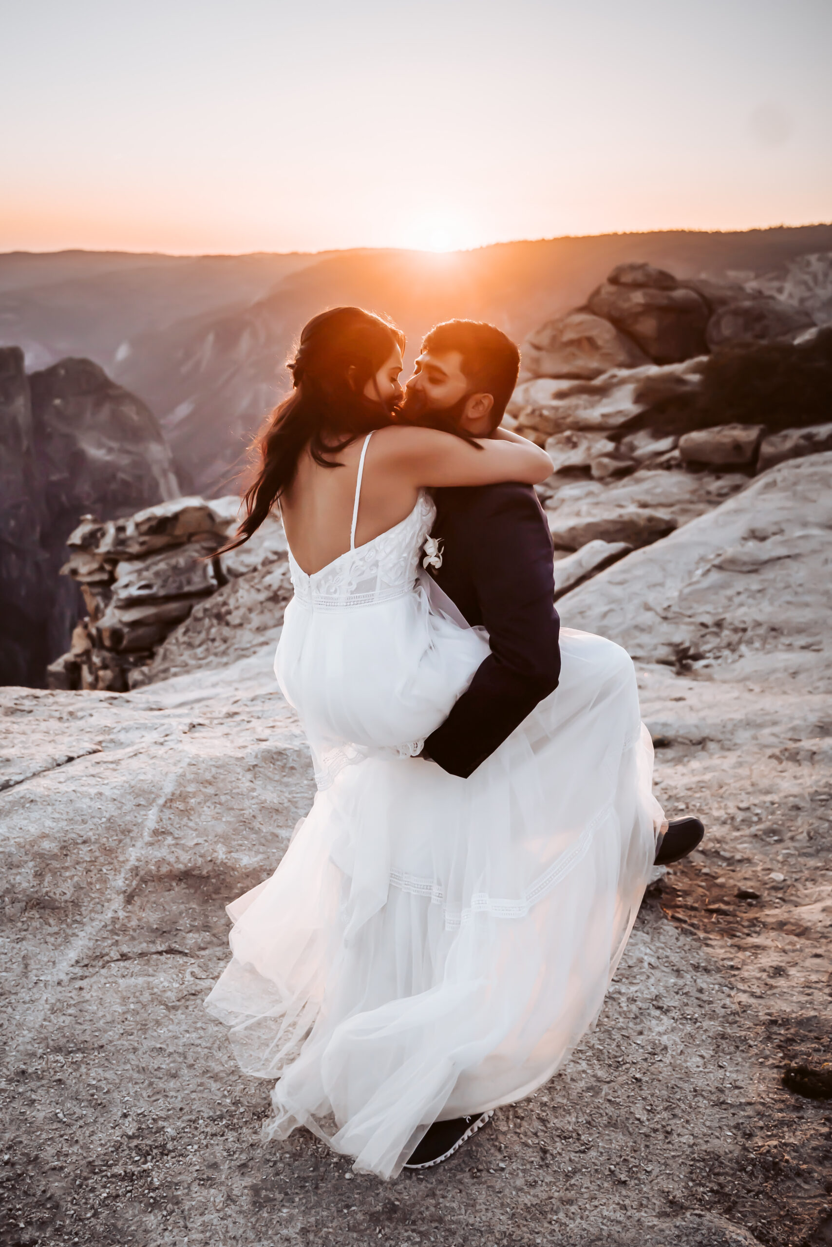 An groom holding his bride in the are overlooking the sunset at Taft Point for their Yosemite Elopement