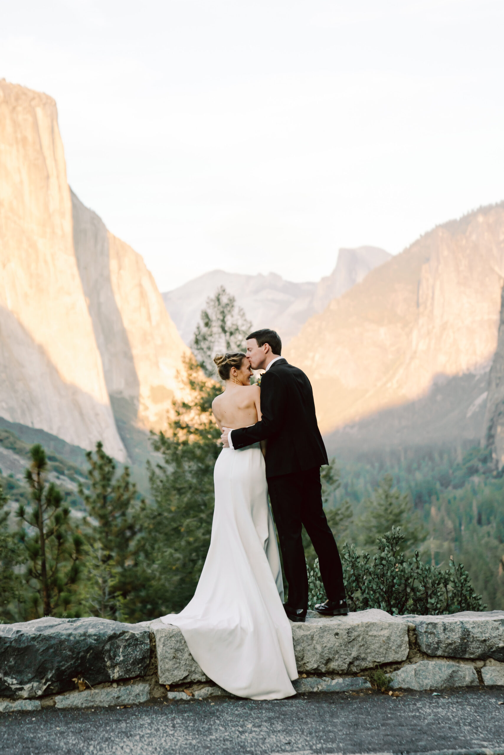 A groom kissing his bride surrounding by the mountains on their elopement day