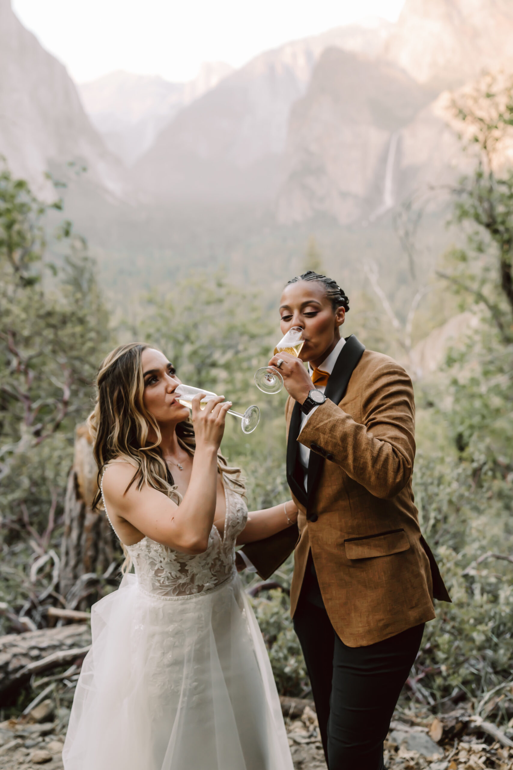 Two brides toasting on their elopement day in front of the mountain backdrop location