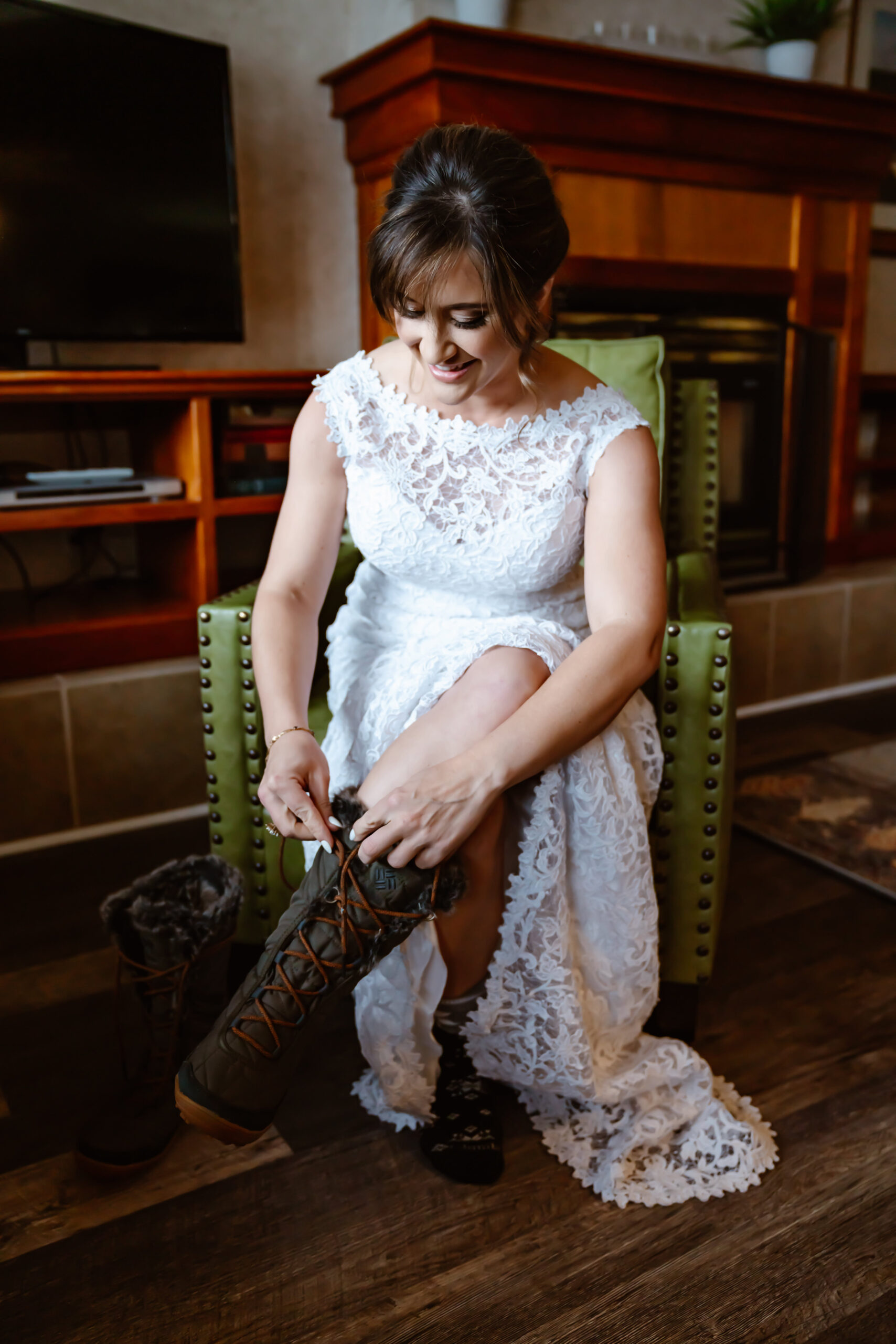 A bride putting on winter boots with her elopement dress