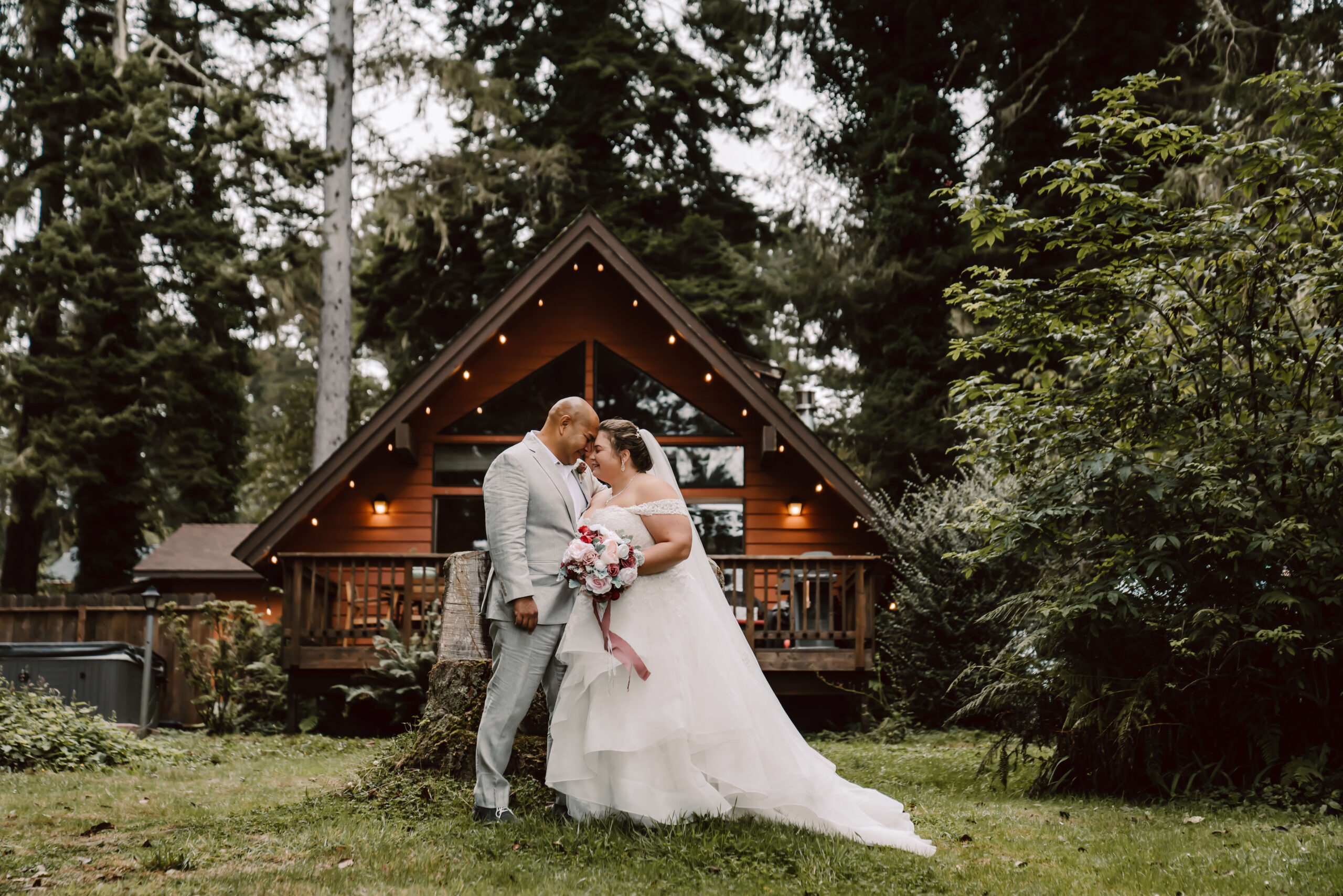 A wedding couple standing in front of an A Frame cabin getting ready for their Northern California Forest Elopement