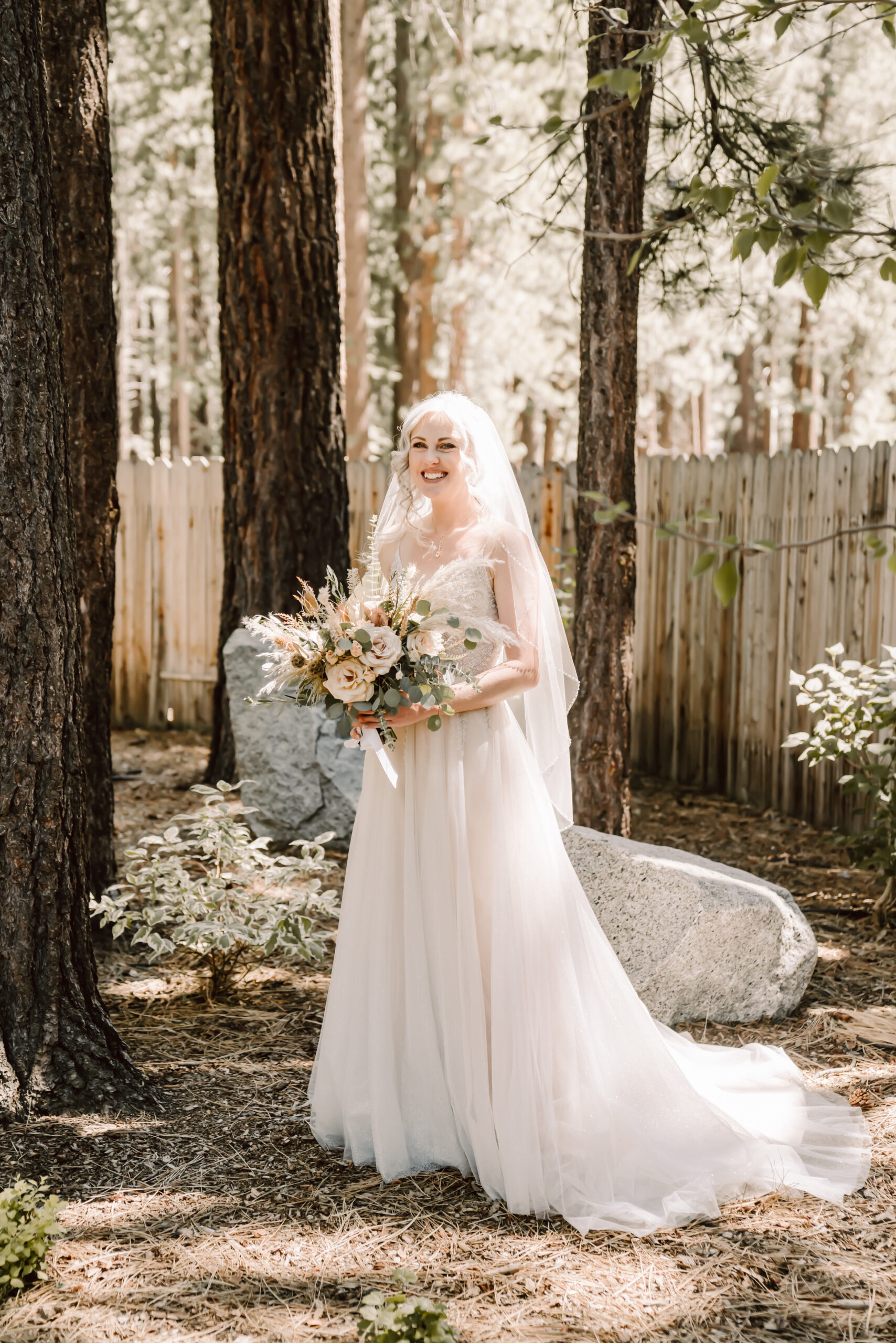 A bride standing in the forest wearing a flowy white elopement dress