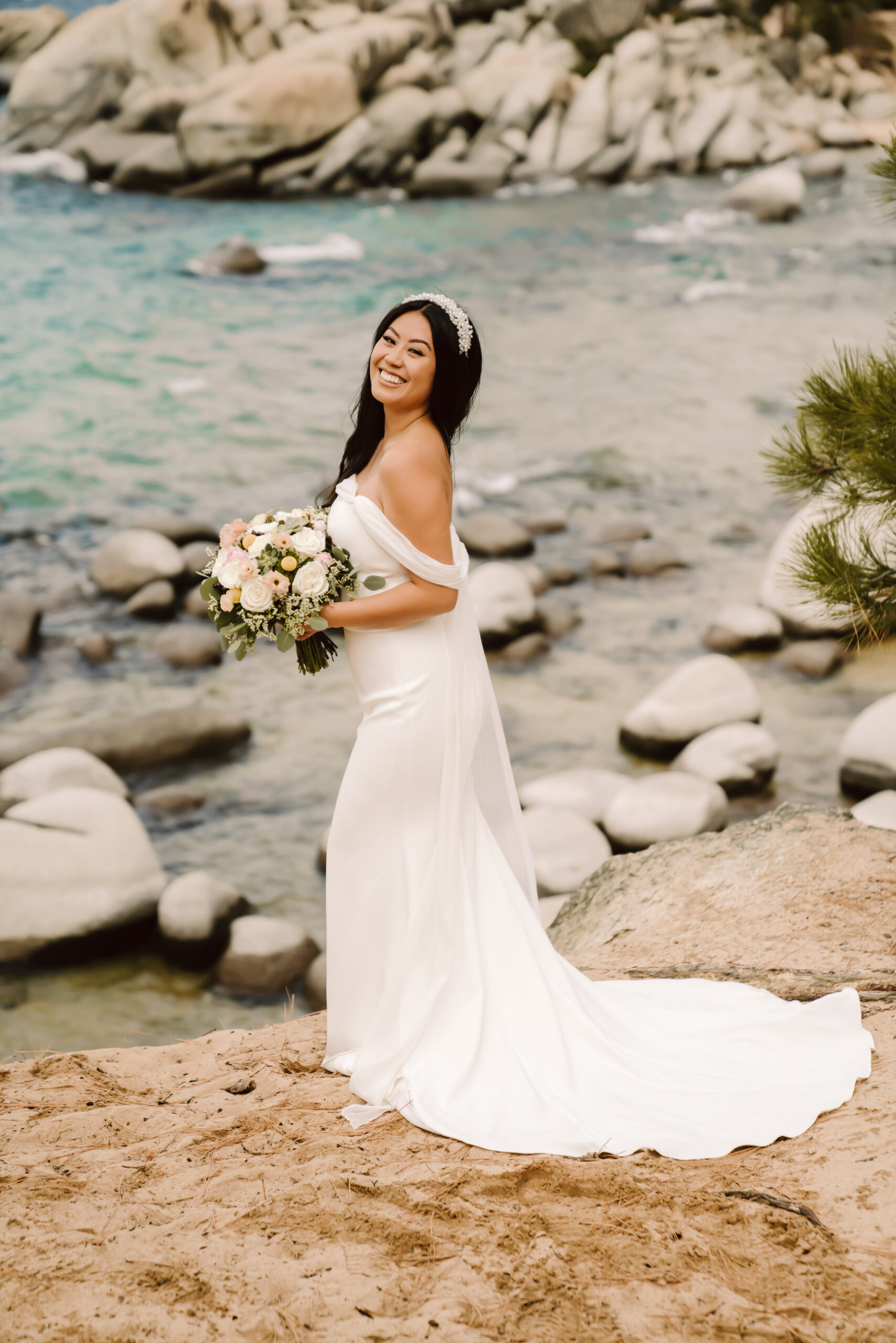 A bride in a beautiful white dress standing in front of Sand Harbor on her Lake Tahoe Elopement