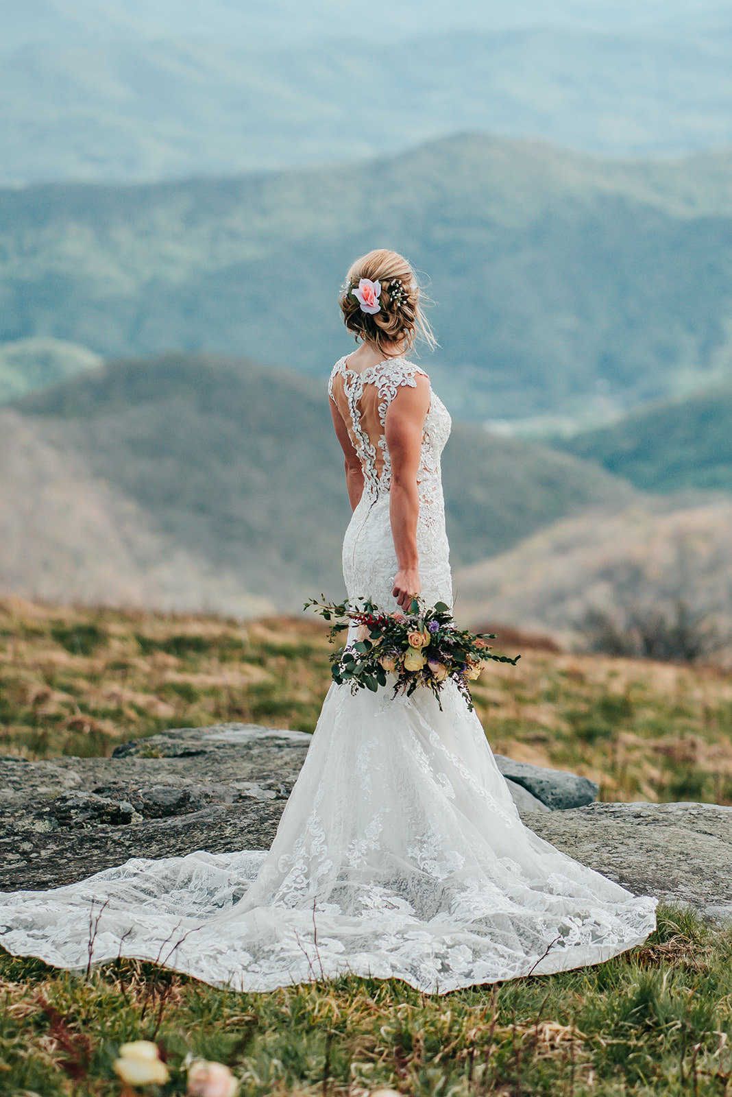 a bride wearing a beautifully laces open back elopement dress looking out onto the mountains