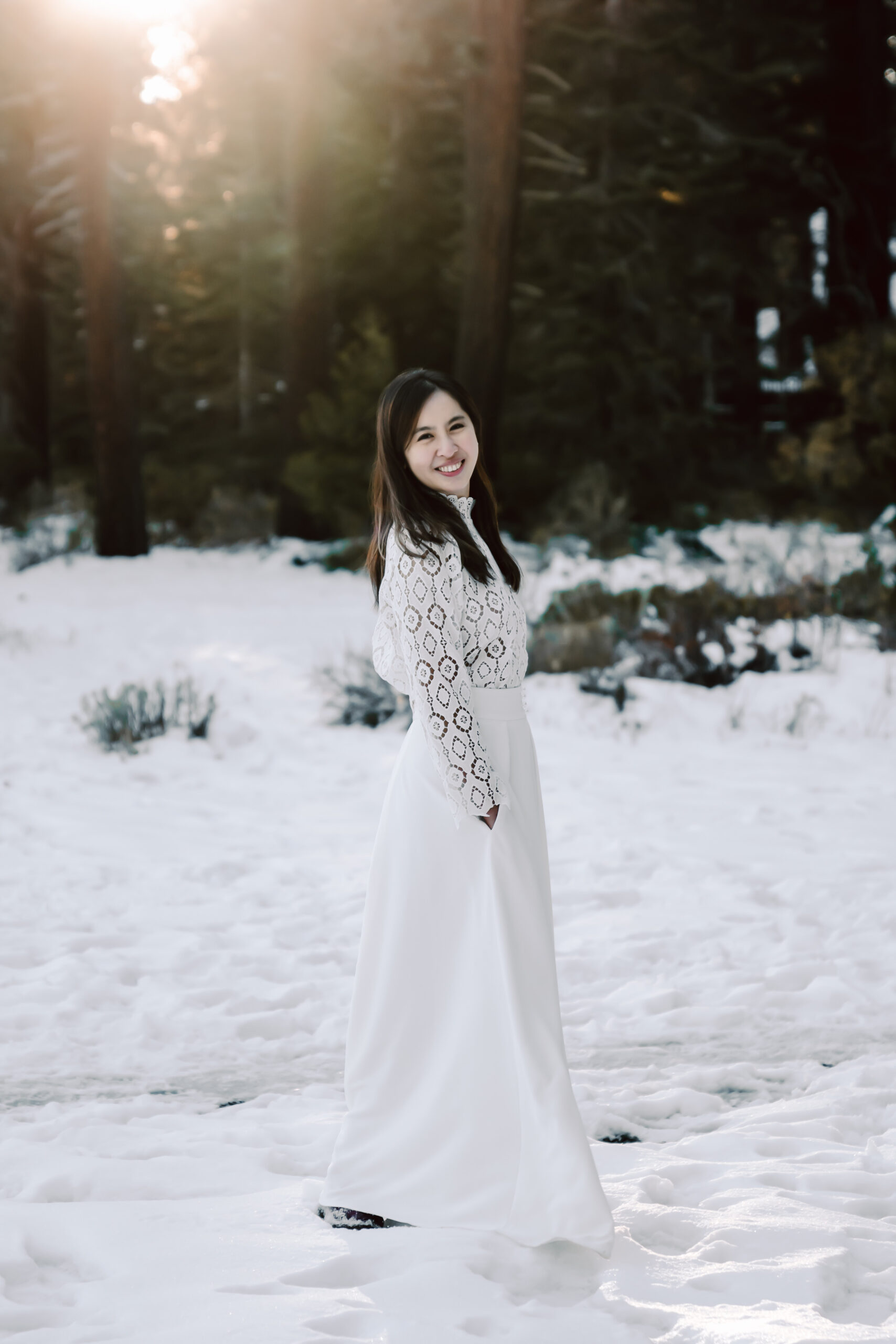 a bride wearing a long sleeve lace elopement dress and standing in the Winter snow