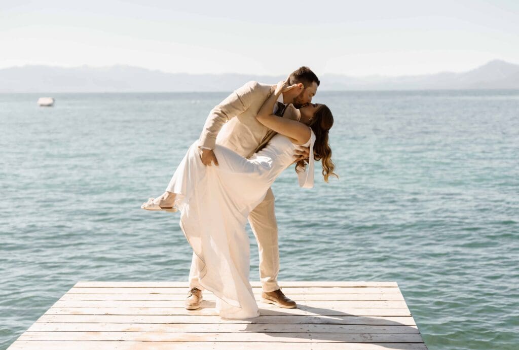 Lake Tahoe summer elopement couple kissing on a dock with blue lake and mountain views in the background