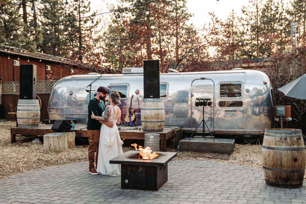 A wedding couple doing thier first dance in front of an airstream and next to a fire pit at South of North Brewing in Lake Tahoe