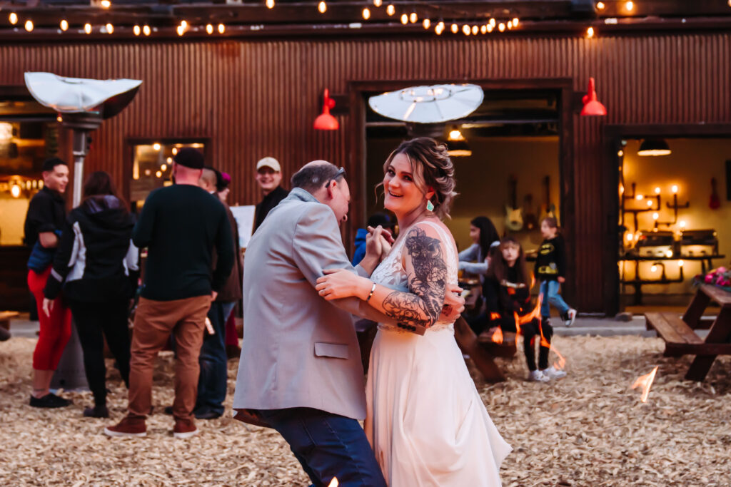 A bride and dad doing first dance next to a fire pit at South of North Brewing in Lake Tahoe for their wedding day