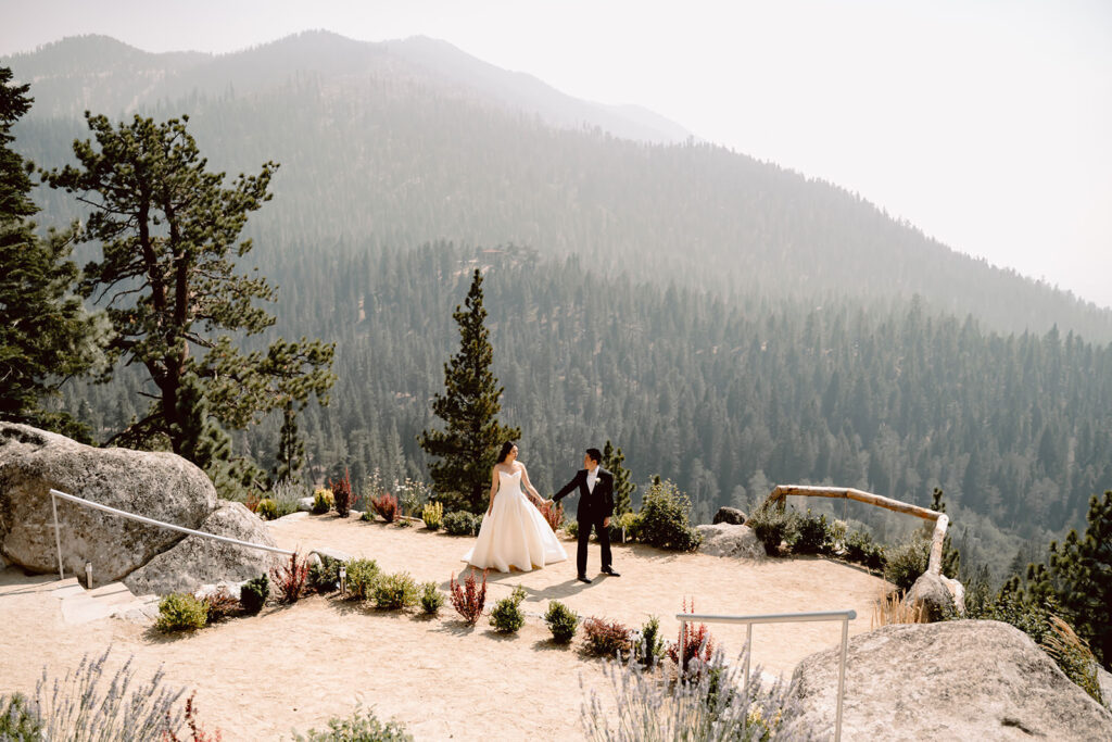 A wedding couple walking on the view point at the Tahoe Blue Estate in Lake Tahoe with the mountains in the background