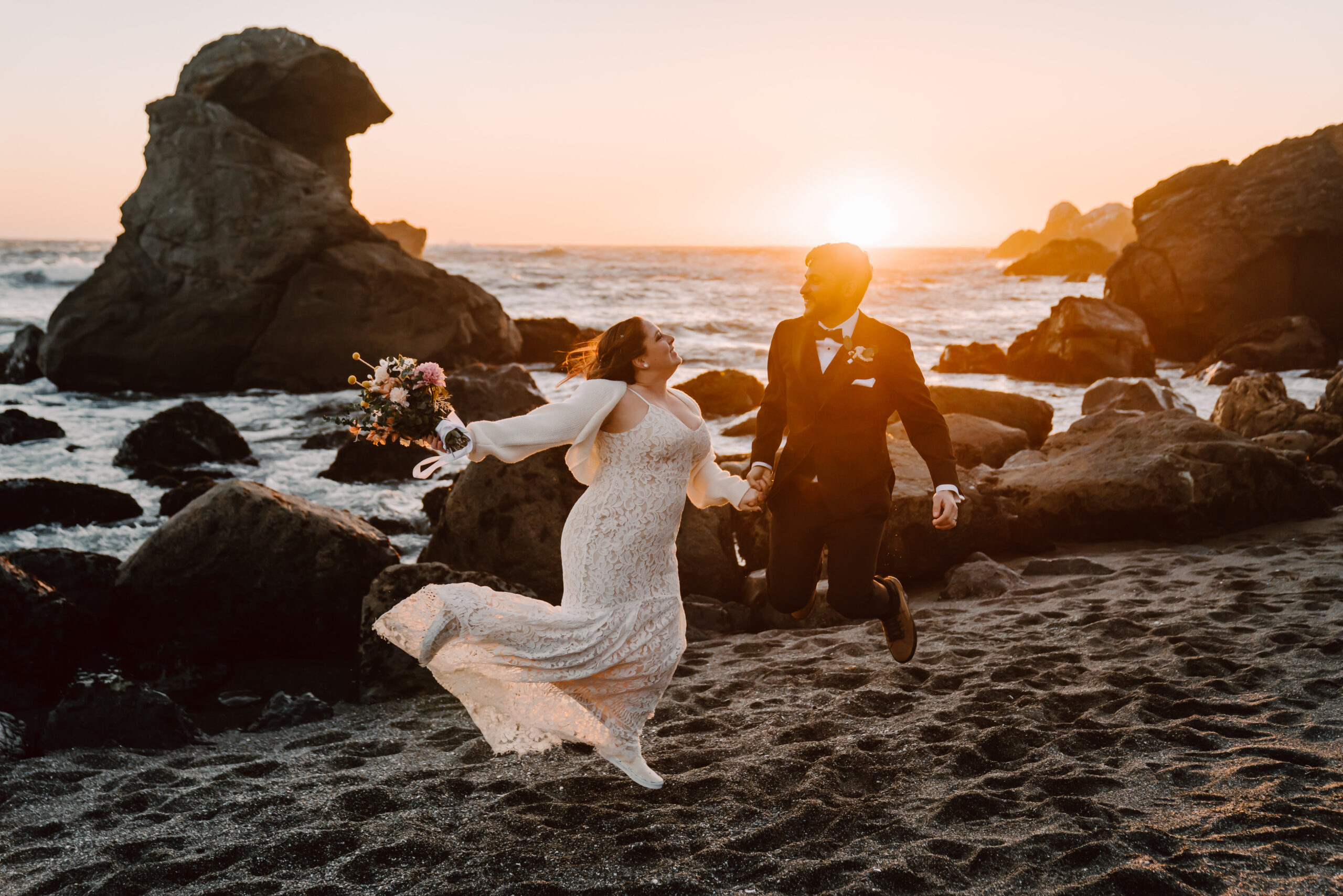 A elopement couple jumping on the beach during sunset for their elopement in Northern California