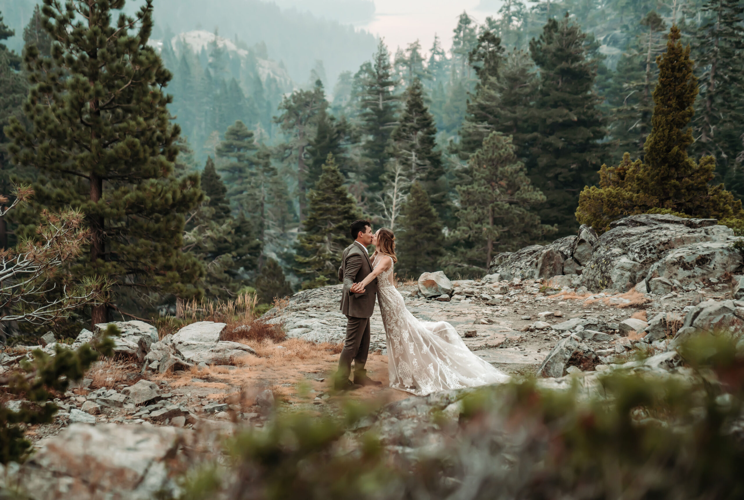 A wedding couple kissing in the mountains overlooking Emerald Bay in Lake Tahoe for their elopement day