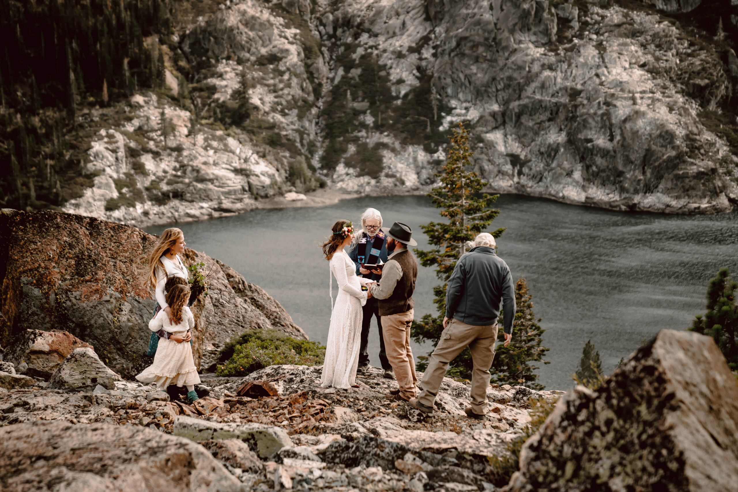 A couple getting married in front of a mountain lake in Northern California with a couple of their friends and family