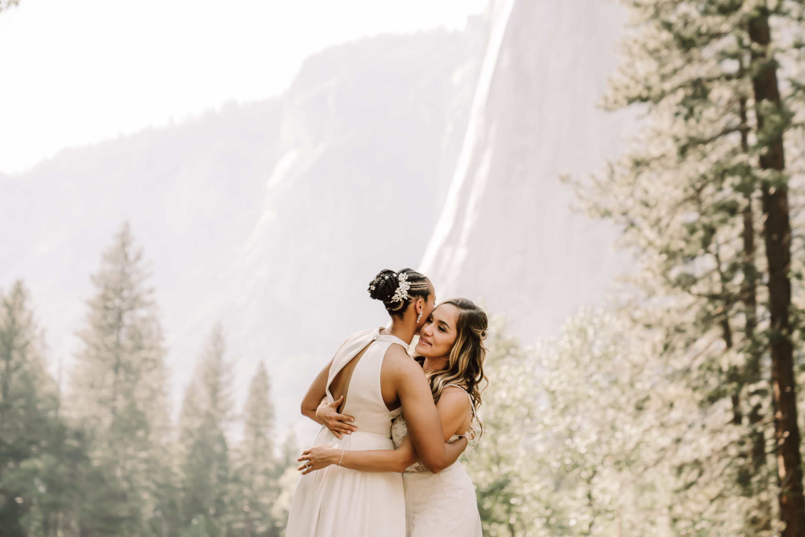 Two brides hugging each other with mountains in the backdrop during their Yosemite Elopement 