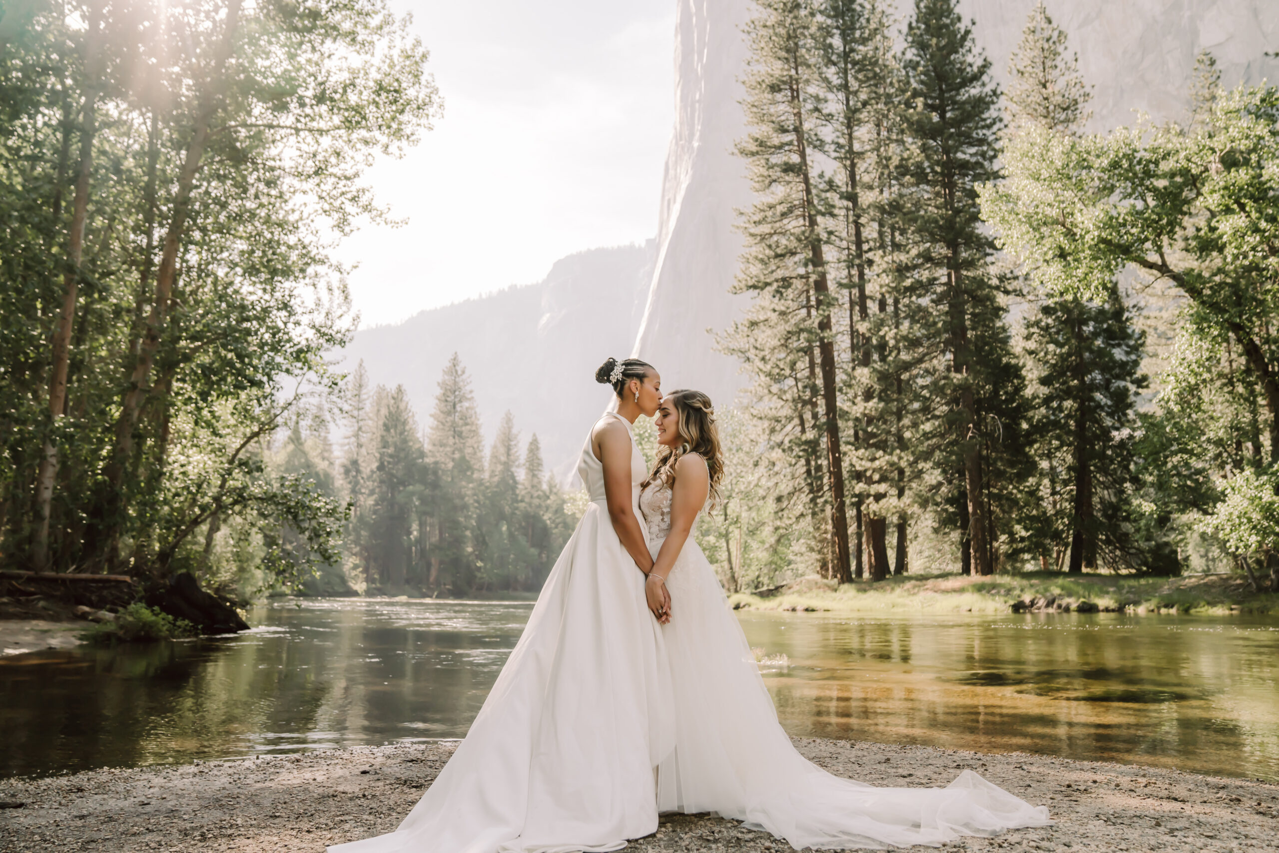 Two brides holding hands and facing each other at Cathedral Beach in Yosemite Valley for their elopement day 