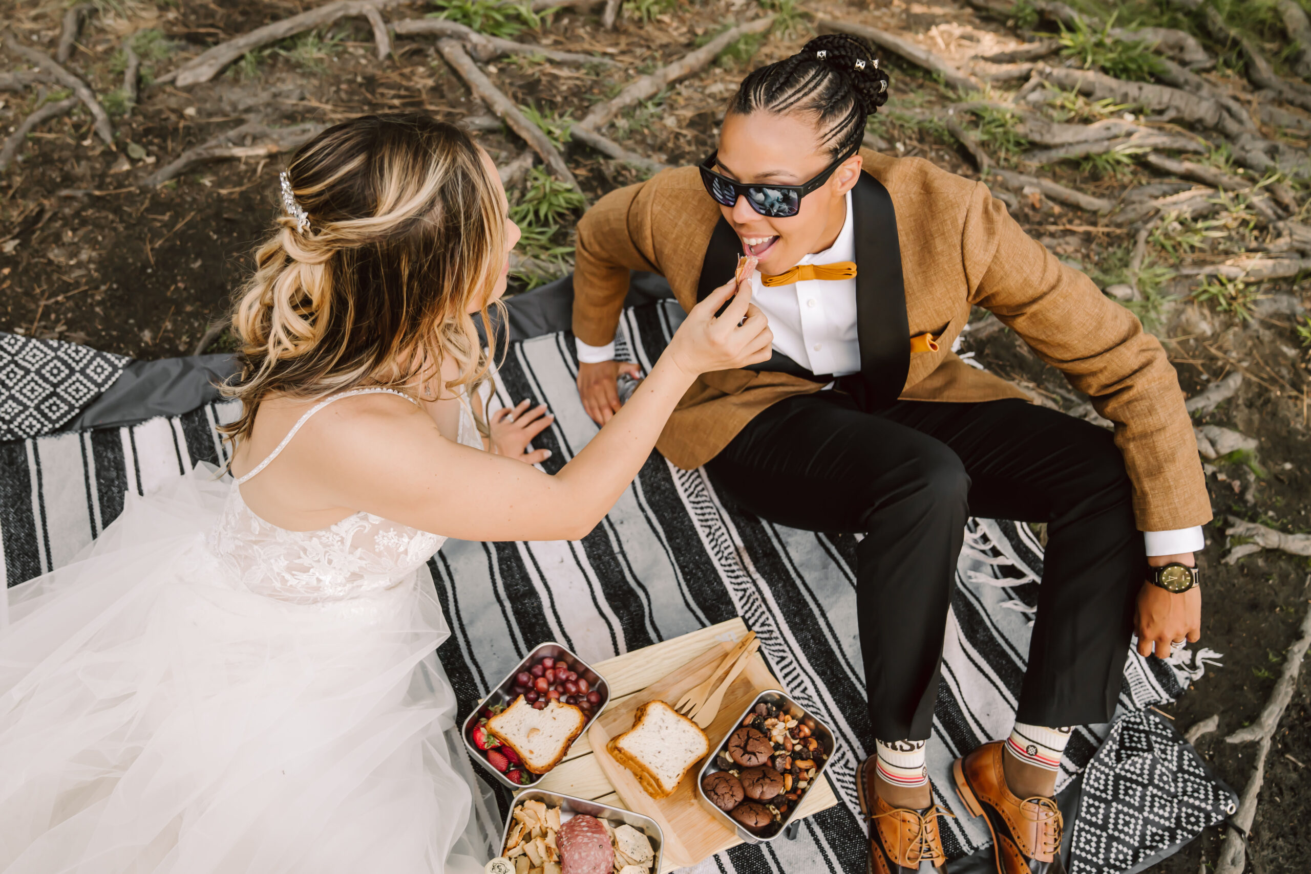 A bride feeding her wife a strawberry during their picnic on their Yosemite Elopement day