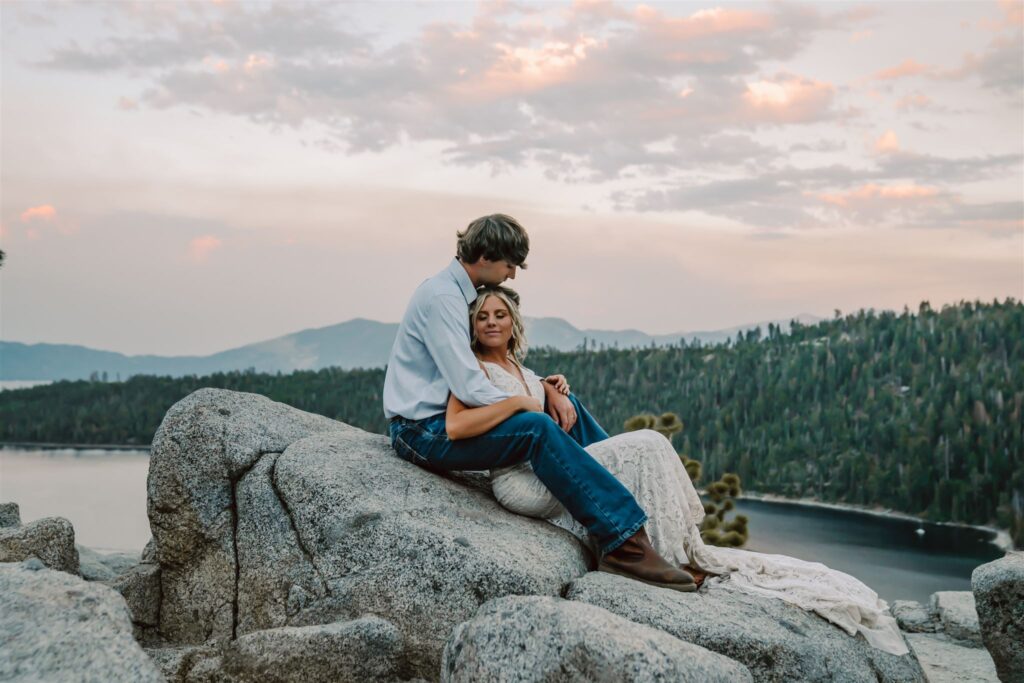 A wedding couple sitting on a rock overlooking a sunset at Emerald Bay for their elopement day