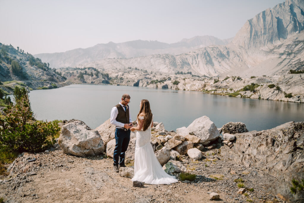 A wedding couple reading their vows surrounded by giant mountains and a lake