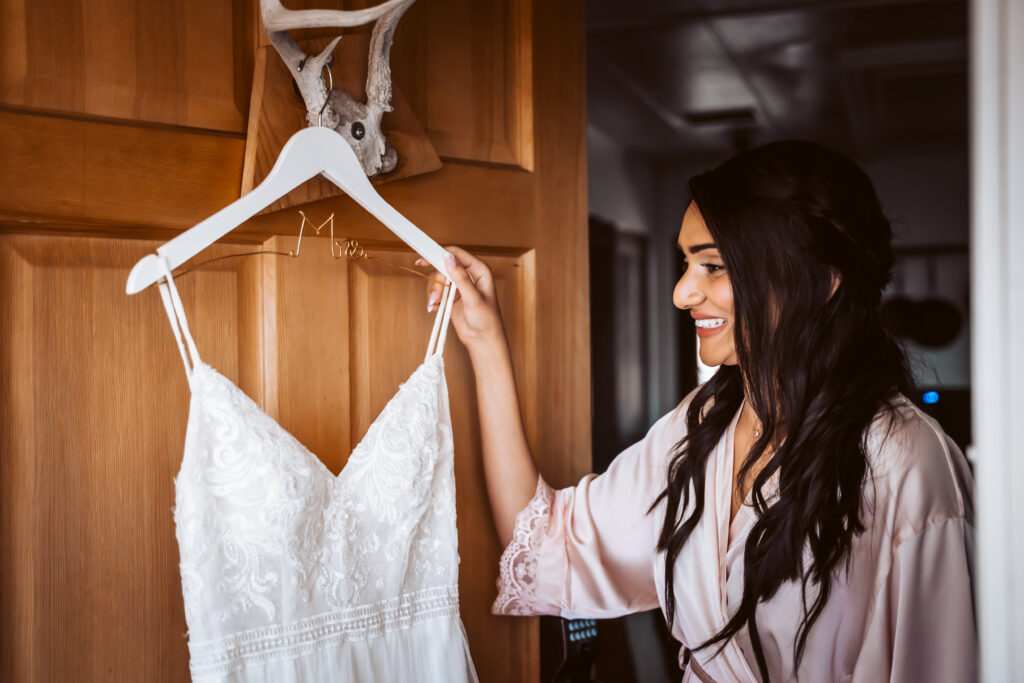 A bride looking at her dress hanging on the door of her airbnb on her wedding day