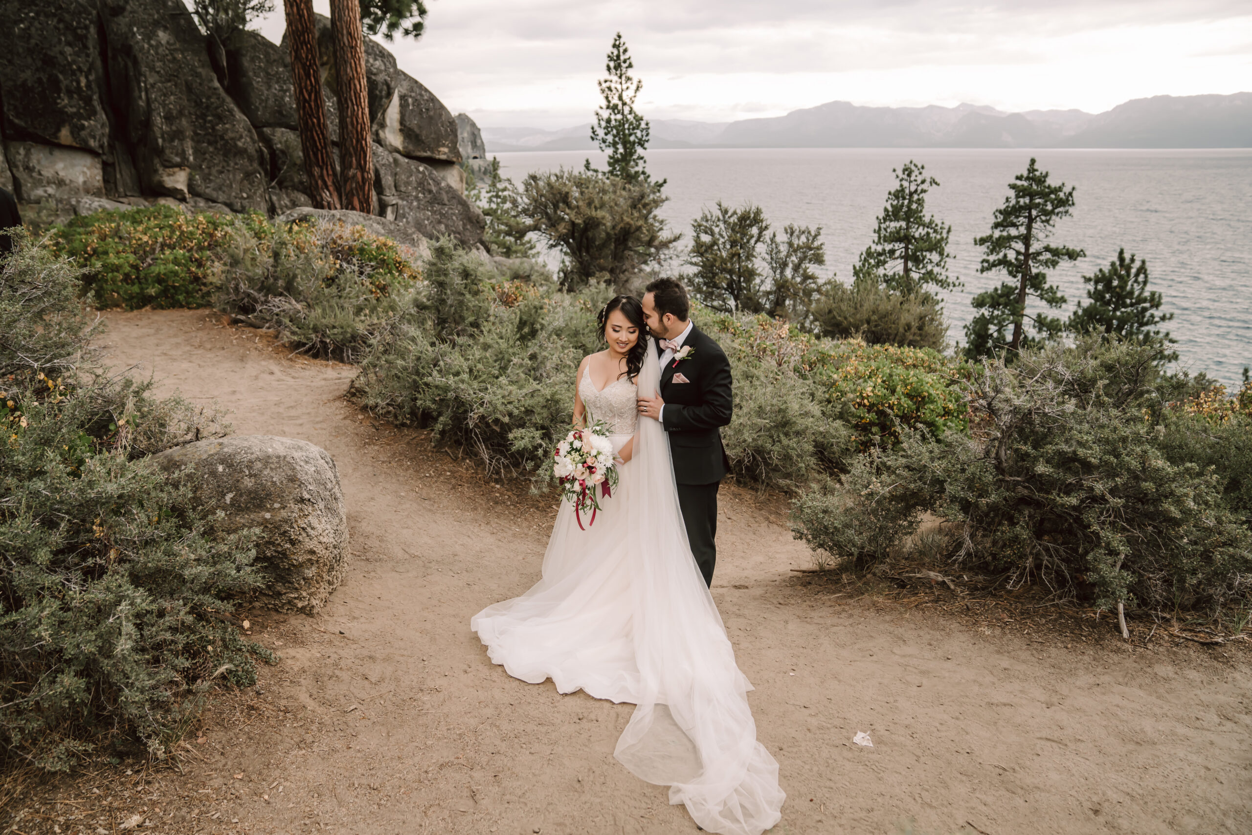 A bride and groom standing in the trees overlooking Lake Tahoe for their Elopement day