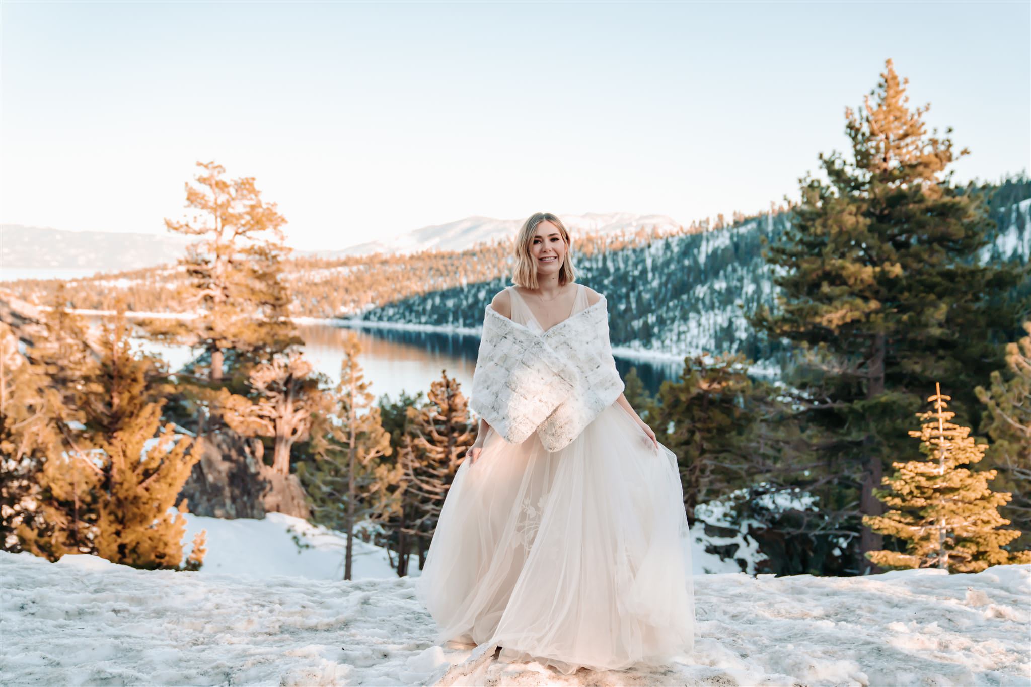 A bride standing in snow overlooking Emerald Bay for her wedding day