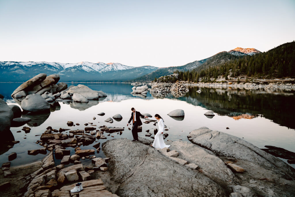 A wedding couple walking on the rocks overlooking the mountains of Lake Tahoe for their wedding day