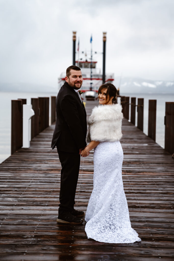 A wedding couple holding hands but looking back on the dock in Lake Tahoe for their wedding day