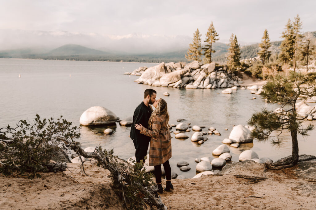 A couple kissing in front of Lake Tahoe at Sand Harbor