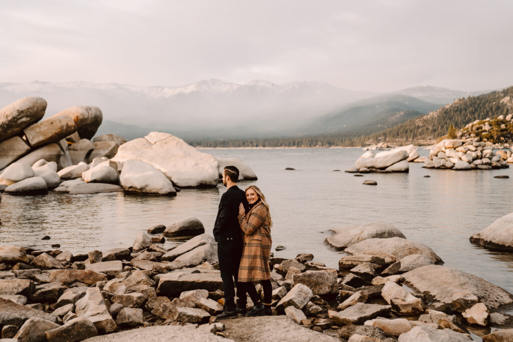 a girl resting her head on a guys back and standing on some boulders in Lake Tahoe