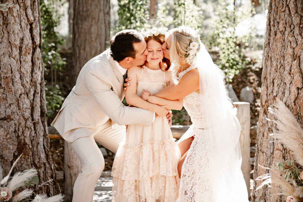 The bride and groom kissing their daughter at their wedding