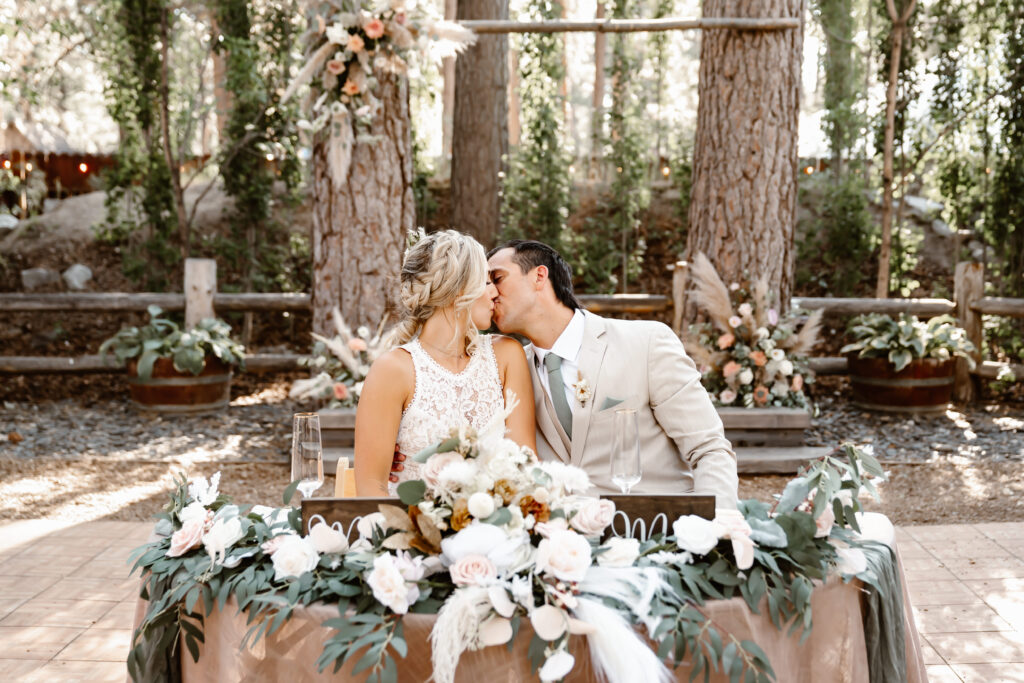 A bride and groom kissing at their head table for their wedding 