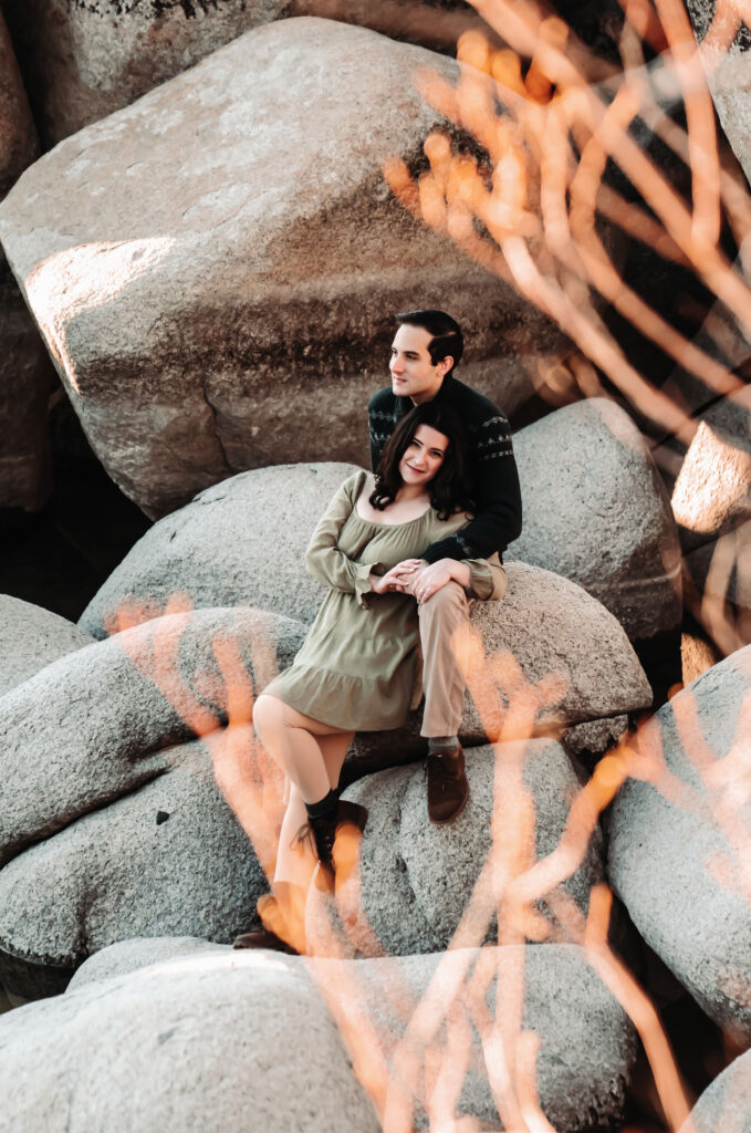 a boy holding his girlfriend and sitting on some boulders in Lake Tahoe