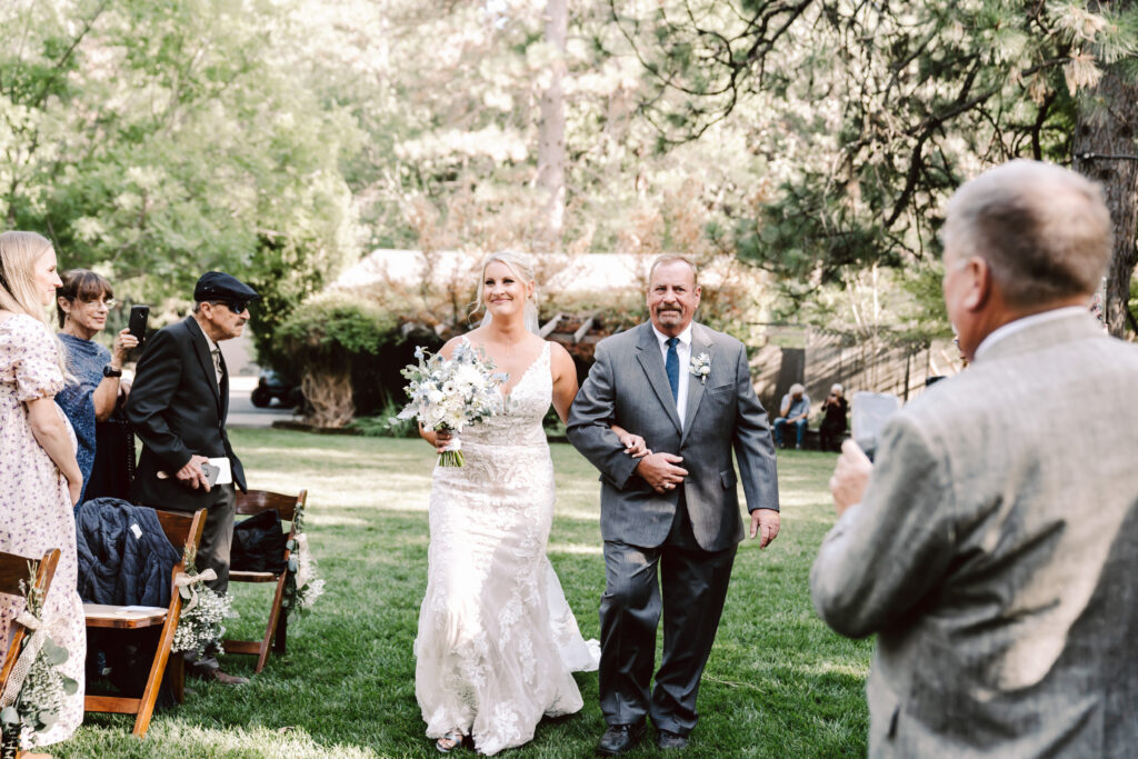 a bride getting walked down the aisle by her dad during her wedding ceremony in Nevada City