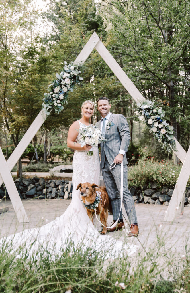 a bride and groom with their dog on their wedding day