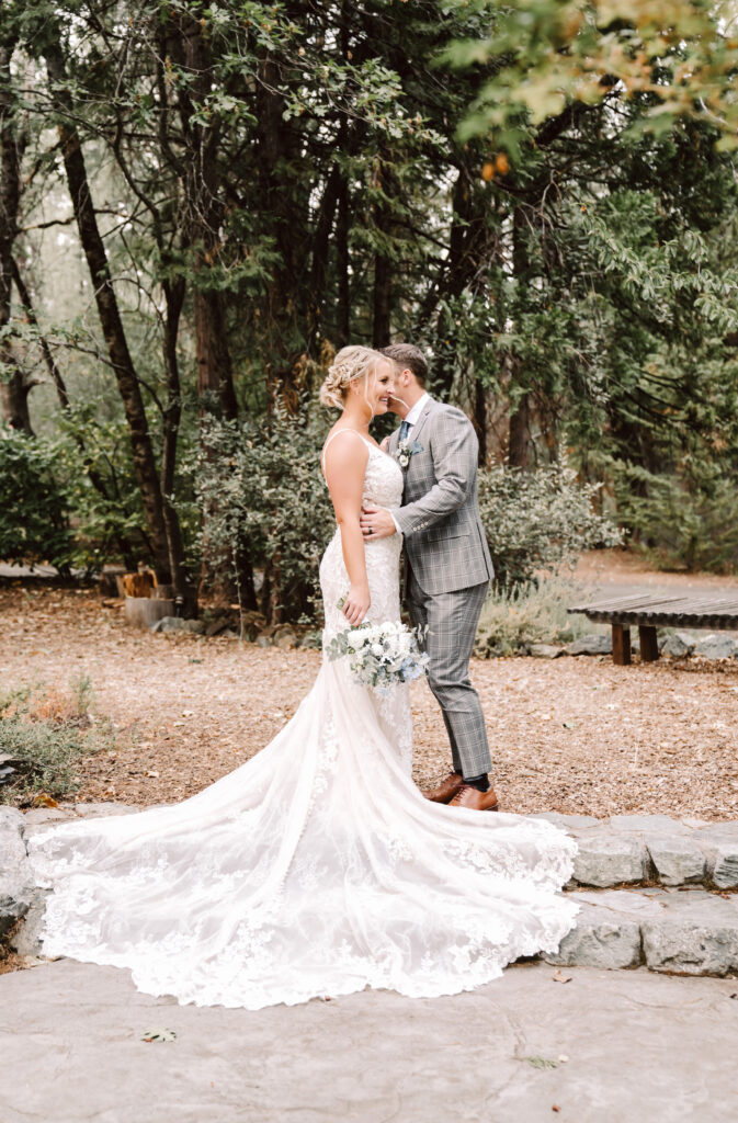 a groom kissing his new wife after their wedding in the forest surrounded by trees at the Roth Estate in Nevada City, CA