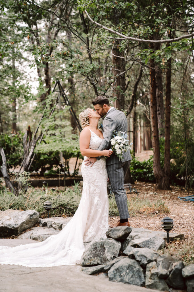 A bride and groom kissing on their wedding day in the forest