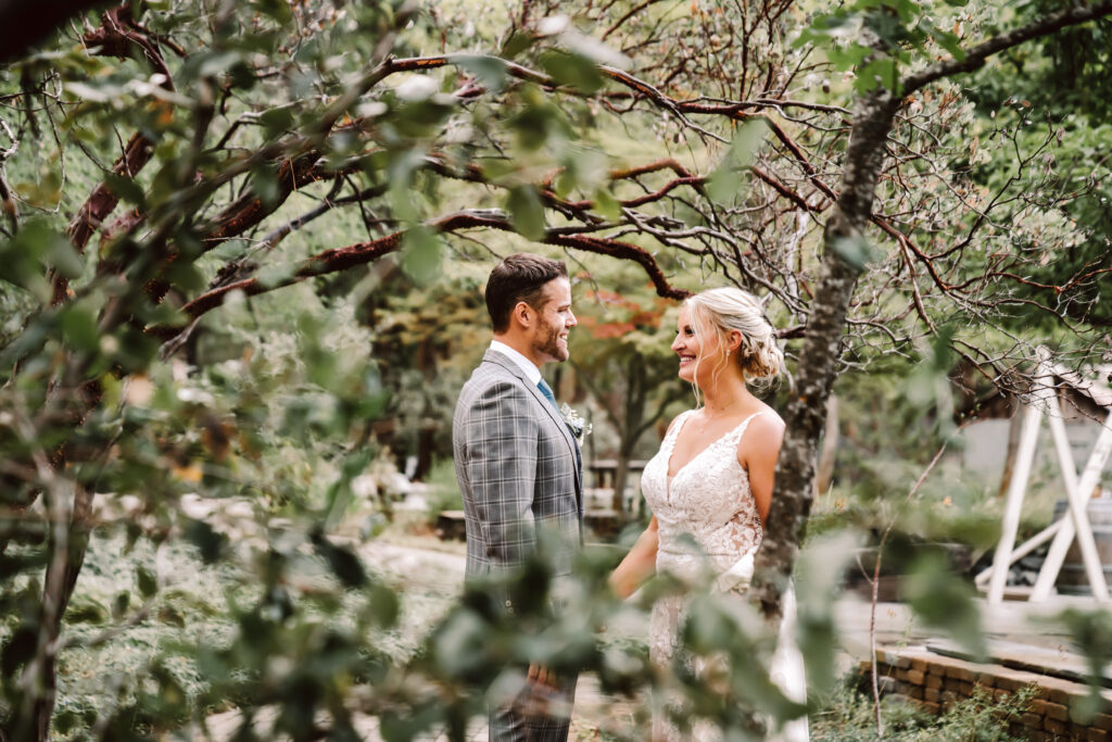 the bride and groom looking at each other in the trees at the Roth Estate for their wedding